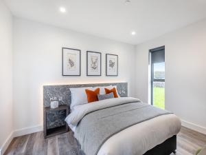 a white bedroom with a large bed with orange pillows at Cybi Lodge 6 - Uk42798 in Llangefni
