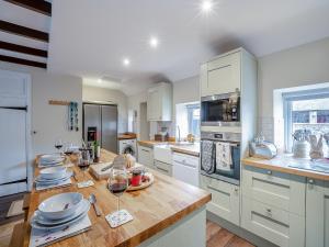 a kitchen with white cabinets and a wooden counter top at The Old Cottage - Uk49169 in Beadnell