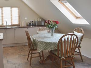 a kitchen with a table and chairs with a vase of flowers at Forest Cottage in Northwold