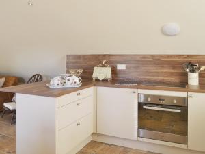 a kitchen with white cabinets and a wooden counter top at Forest Cottage in Northwold