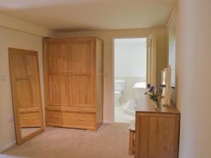 a bathroom with a large wooden cabinet and a toilet at Forest Cottage in Northwold +5 photos
