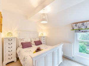 a bedroom with a white bed and a window at Adair Cottage in Wigglesworth