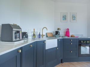 a kitchen with blue cabinets and a microwave at The Nest - Uk50122 in Bodelwyddan