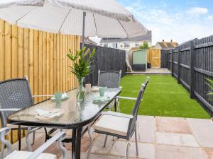 a patio with a table and chairs and an umbrella at Wick Cottage in Nottage