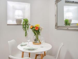 a white table with a vase of flowers and two mirrors at Wick Cottage in Nottage