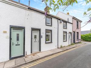 a row of white houses with green doors on a street at Wick Cottage in Nottage