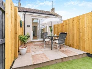 a patio with a table and chairs and an umbrella at Wick Cottage in Nottage +8 photos