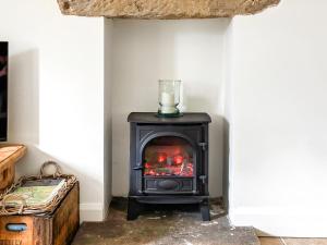 a stove in the corner of a room at Bank Cottage in Grindleford Bridge