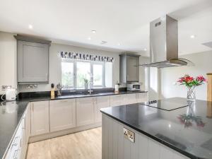 a kitchen with white cabinets and black counter tops at Upper Bryn Y Groes in New Bridge +22 photos