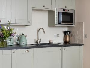 a white kitchen with a sink and a microwave at Running Hare - Uk7558 in Inverness