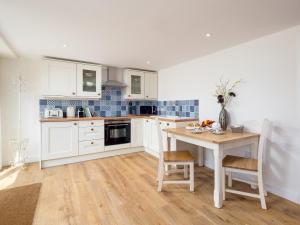 a kitchen with white cabinets and a table with chairs at Barn End - Uk32694 in Horton