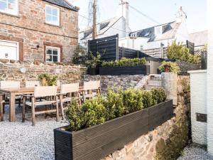 a patio with a table and chairs and plants at Auchengool House in Kirkcudbright