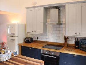 a kitchen with blue cabinets and a white refrigerator at Y-Beudy Bach - Uk51421 in Llandeilo +8 photos