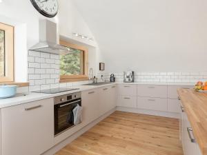 a kitchen with white cabinets and a clock on the wall at Jill Strawbale House- Ukc2935 in Strontian