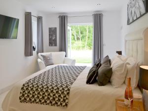 a bedroom with a bed with a chair and a window at Honey Pippin in Cheriton Bishop
