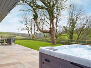 a hot tub on a patio with a table and chairs at Cwm Hyfryd in Llanboidy