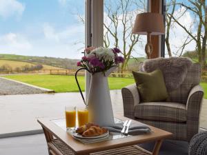 a coffee table with a vase of flowers and drinks at Cwm Hyfryd in Llanboidy