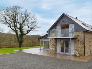 a brick house with a balcony and a tree at Cwm Hyfryd in Llanboidy