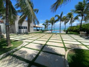 a patio with palm trees and a swimming pool at Luxo e pé na areia in Parnamirim