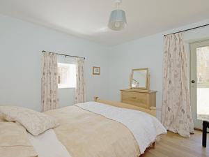 a white bedroom with a bed and a mirror at Dale House in Castleton