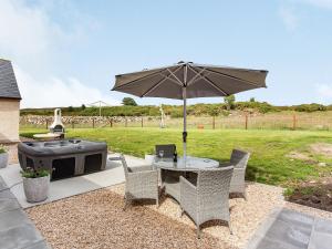 a table with an umbrella next to a grill at Morven View in Dunbeath