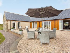 a patio with a table and chairs and an umbrella at Morven View in Dunbeath +29 photos
