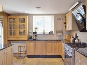 a large kitchen with wooden cabinets and a window at Brixton Barn in Mottistone