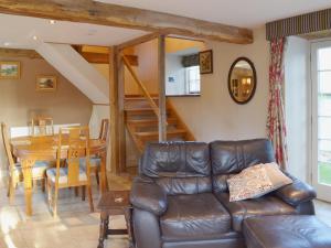 a living room with a leather couch and a table at Brixton Barn in Mottistone
