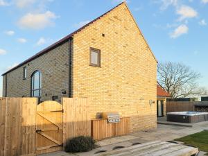 a brick building with a wooden fence in front of it at The Willows - Ukc4617 in Dunholme