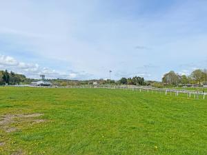 a green field with a white fence in the distance at Barngarth in Cartmel