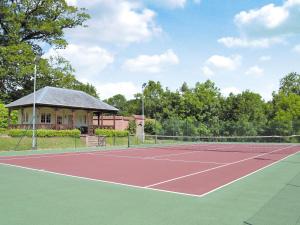 a tennis court with a house in the background at Garden Cottage in Westleigh