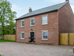 a red brick house with a wooden fence at Chestnuts in Burgh by Sands