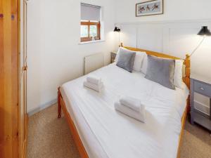 a bedroom with a large white bed with two pillows at Elm Cottage-Uk2791 in Penmaen-mawr