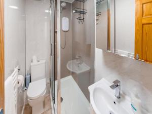 a white bathroom with a toilet and a sink at Elm Cottage-Uk2791 in Penmaen-mawr
