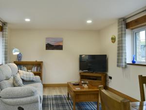 a living room with a couch and a tv at Bluebell Barn in Okehampton