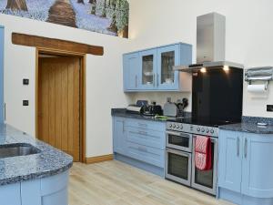 a kitchen with blue cabinets and a stove top oven at Bluebell Barn in Okehampton