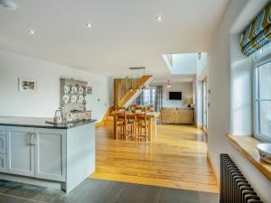 a kitchen and living room with a staircase in the background at Deri Cottage in Chwilog