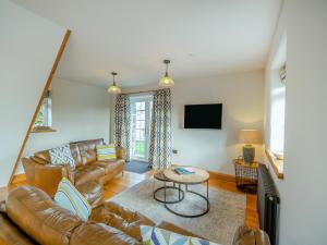 a living room with a leather couch and a table at Deri Cottage in Chwilog