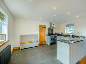 a large kitchen with white cabinets and a counter top at Deri Cottage in Chwilog