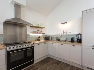a kitchen with white cabinets and a stove top oven at The Barn At Toft Hill Hall in High Etherley