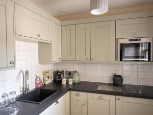 a kitchen with white cabinets and a sink at Courtyard - Uk7554 in Inverness