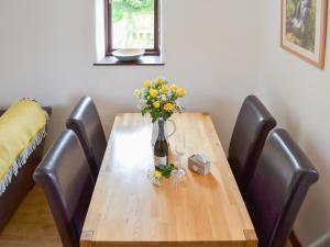 a wooden table with a vase of flowers on it at Sunset in Cheriton Bishop