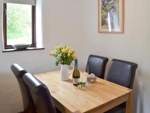 a wooden table with a bottle of wine and flowers on it at Sunset in Cheriton Bishop
