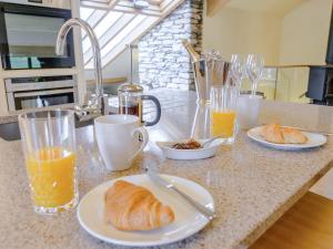 a kitchen counter with glasses of orange juice and croissants at Mungeon Barn - Uk30125 in Backbarrow