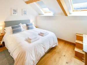 a bedroom with a bed with white sheets and blue pillows at The Oak Stall - Uk11023 in East Worlington +15 photos
