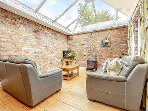 a living room with two couches and a brick wall at The Stables - Uk47151 in Burgh le Marsh