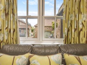a couch in a living room with a large window at The Stables - Uk47151 in Burgh le Marsh