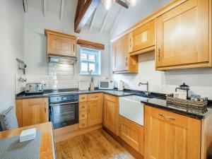 a kitchen with wooden cabinets and a sink at The Stables - Uk47151 in Burgh le Marsh