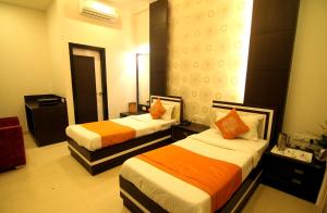 Habitación de hotel con 2 camas con sábanas de color naranja y blanco en Hotel Rivera Palace, en Varanasi