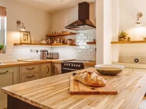 a kitchen with a cutting board with a loaf of bread on a counter at Gatehouse North in Worstead